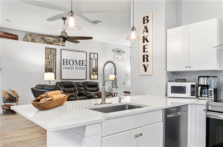 Kitchen with white cabinetry, light stone countertops, a peninsula, open floor plan, and stainless steel appliances