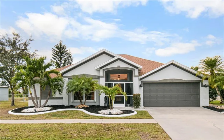 Ranch-style home with driveway, a garage, a front yard, and stucco siding