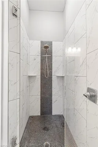 Full bath with a marble finish shower