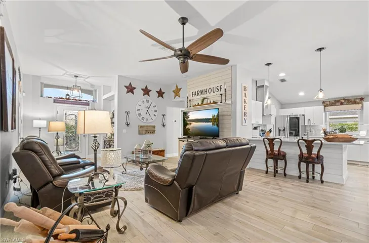 Living area with lofted ceiling, ceiling fan, and light wood-style floors