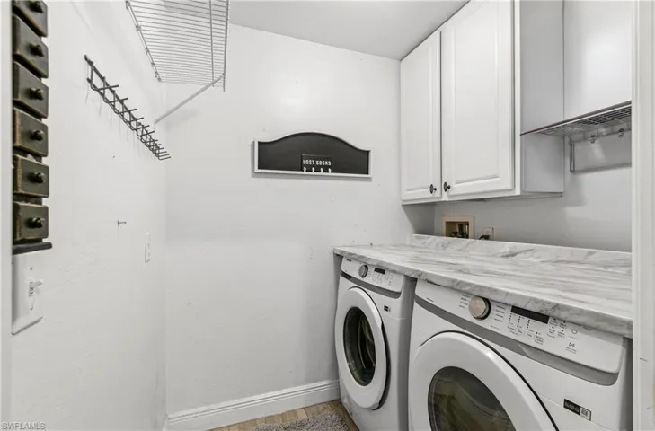 Laundry area with cabinet space, washing machine and clothes dryer, and light wood-style flooring