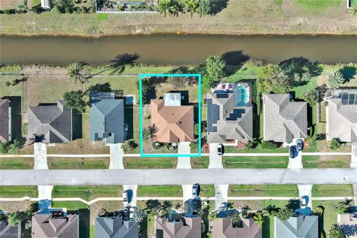 Aerial perspective of suburban area with property parcel outlined and a nearby body of water