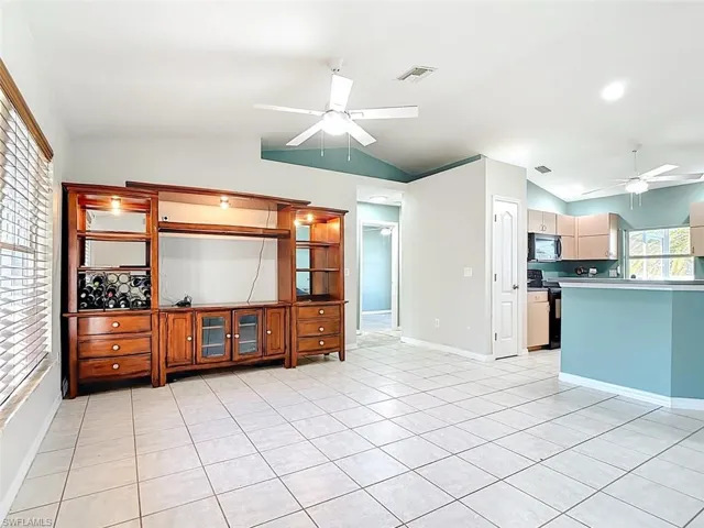 Living room featuring ceiling fan, vaulted ceiling, and light tile patterned flooring