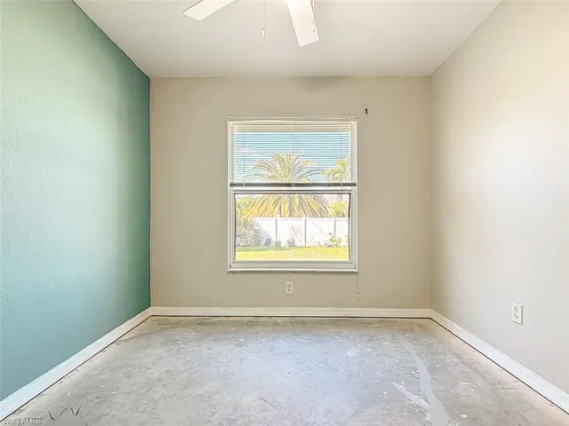 Spare room featuring a textured wall, unfinished concrete flooring, and ceiling fan