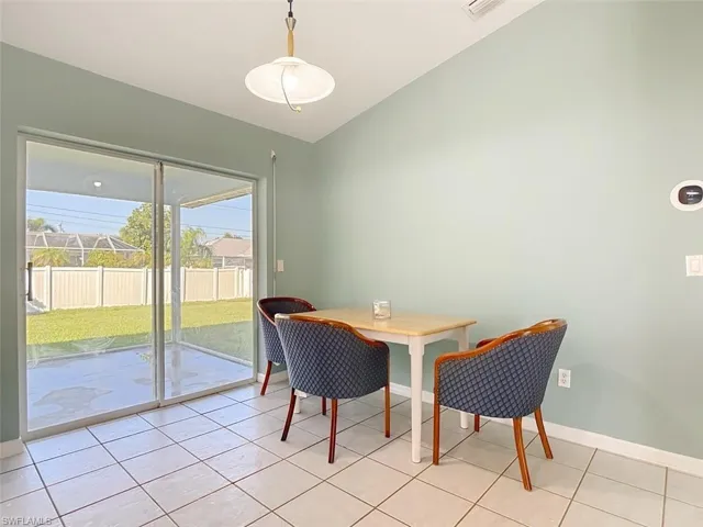 Dining area with light tile patterned floors and vaulted ceiling