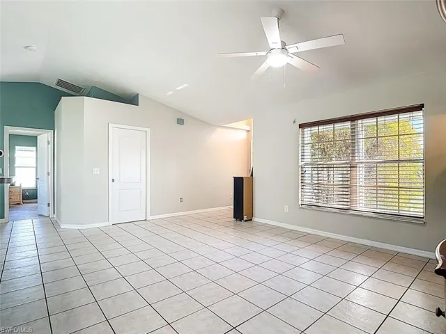 Unfurnished living room with lofted ceiling, a ceiling fan, and light tile patterned flooring