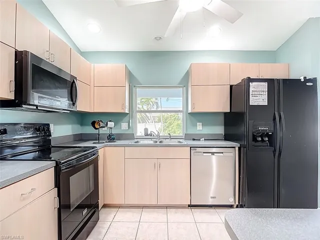 Kitchen with light brown cabinetry, black appliances, light tile patterned floors, recessed lighting, and a ceiling fan