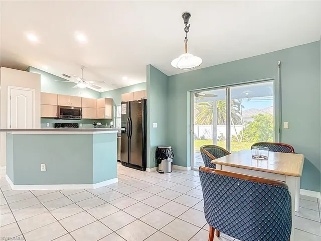 Kitchen featuring ceiling fan, black refrigerator with ice dispenser, pendant lighting, lofted ceiling, and light brown cabinets