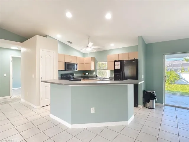 Kitchen with a kitchen island, lofted ceiling, black appliances, light brown cabinetry, and recessed lighting