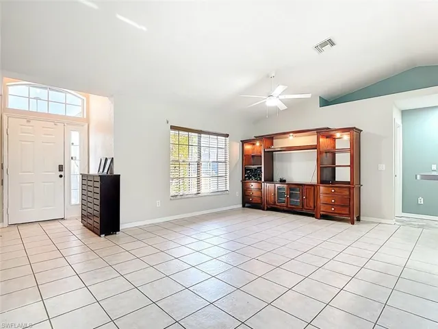 Foyer entrance featuring lofted ceiling, a ceiling fan, and light tile patterned floors