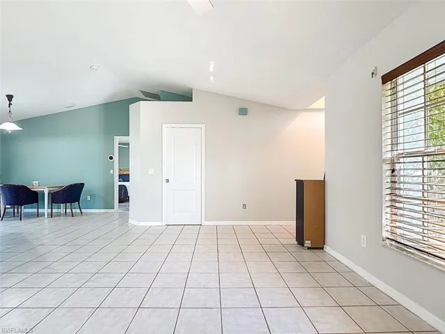 Spare room featuring light tile patterned flooring and vaulted ceiling