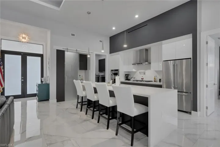 The contemporary kitchen is designed to impress with stainless steel appliances, a gas cooktop with vent hood, built-in microwave, abundant cabinetry with double drawers, generous countertop space, and a large waterfall island that's perfect for entertaining.