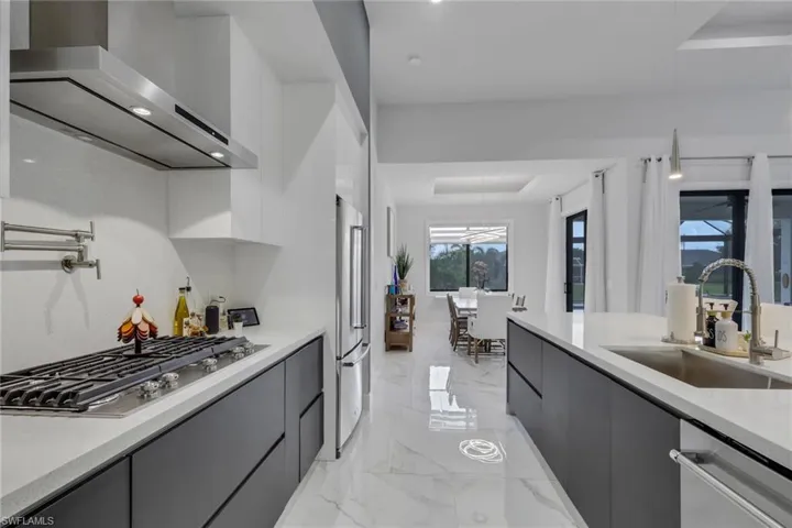 The contemporary kitchen is designed to impress with stainless steel appliances, a gas cooktop with vent hood, built-in microwave, abundant cabinetry with double drawers, generous countertop space, and a large waterfall island that's perfect for entertaining.