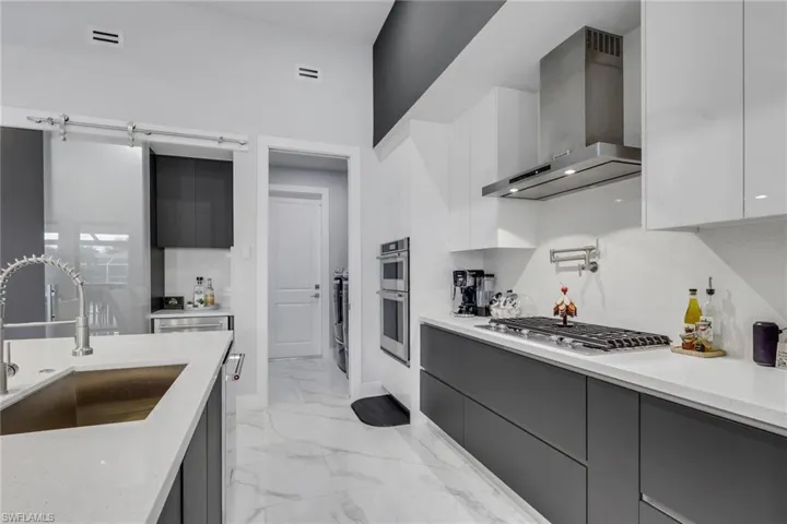 The contemporary kitchen is designed to impress with stainless steel appliances, a gas cooktop with vent hood, built-in microwave, abundant cabinetry with double drawers, generous countertop space, and a large waterfall island that's perfect for entertaining.