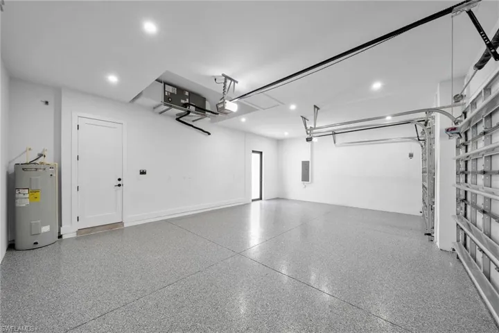 Garage featuring a garage door opener, electric panel, and electric water heater