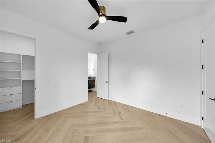 Unfurnished bedroom with ceiling fan, a closet, light parquet flooring, and a spacious closet