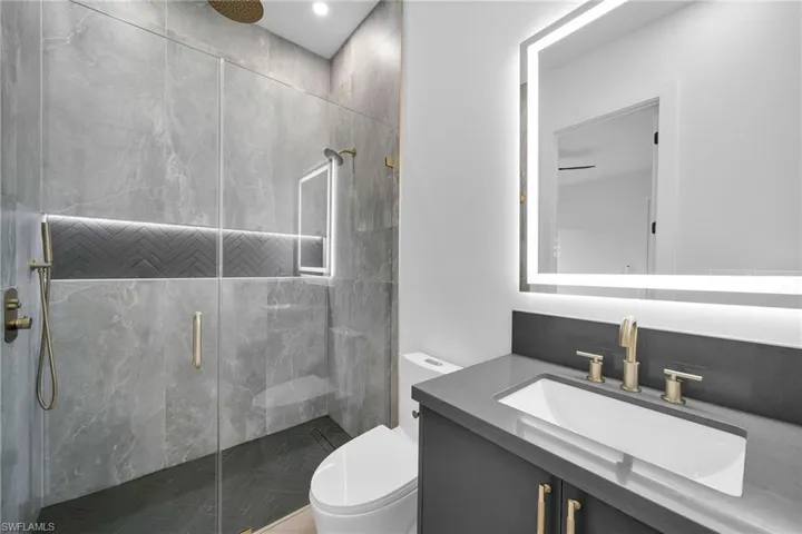 Bathroom featuring vanity, toilet, and a shower with shower door