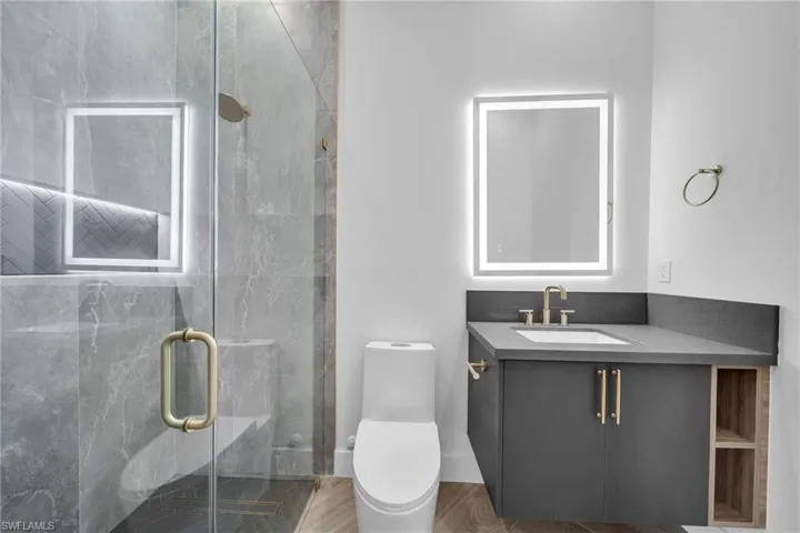 Bathroom with vanity, toilet, and a shower with door