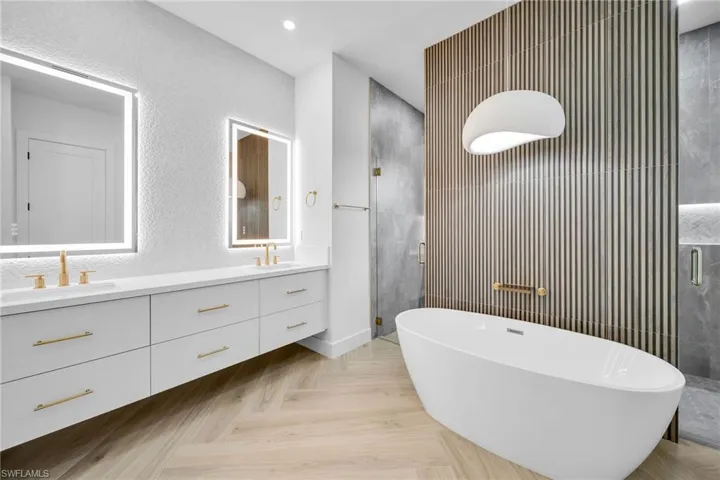 Bathroom featuring independent shower and bath, vanity, and parquet floors