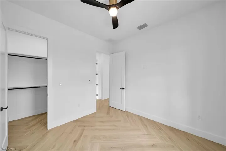 Unfurnished bedroom with light parquet floors, ceiling fan, and a closet