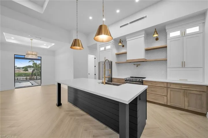 Kitchen featuring decorative backsplash, white cabinets, hanging light fixtures, and a spacious island