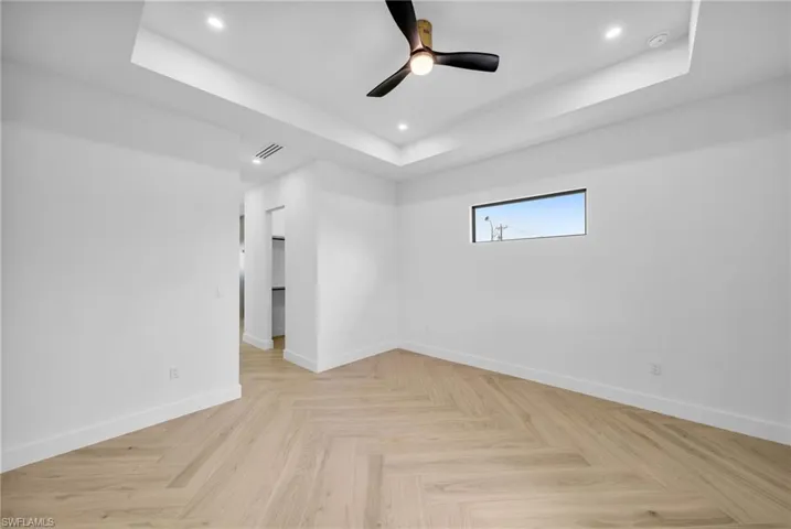 Empty room featuring ceiling fan, a raised ceiling, and light parquet floors