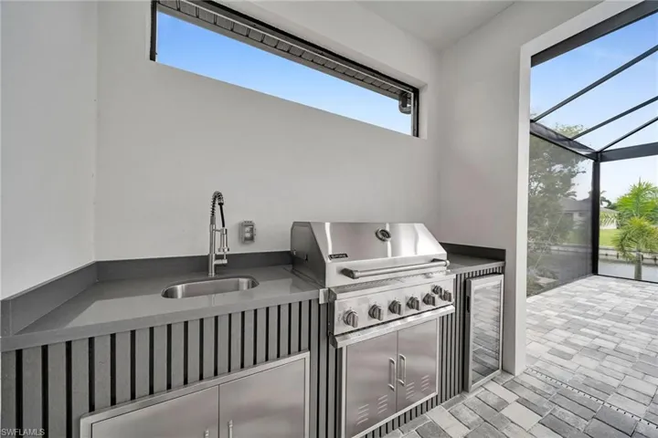 View of patio / terrace featuring a lanai, area for grilling, sink, and a grill