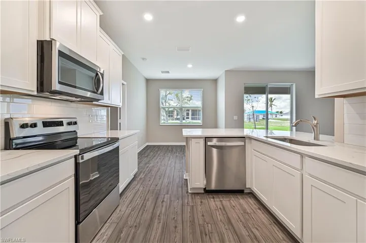 Kitchen with a wealth of natural light, stainless steel appliances, tasteful backsplash, and sink