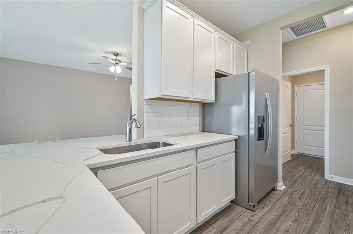 Kitchen with white cabinetry, hardwood / wood-style flooring, sink, tasteful backsplash, and ceiling fan