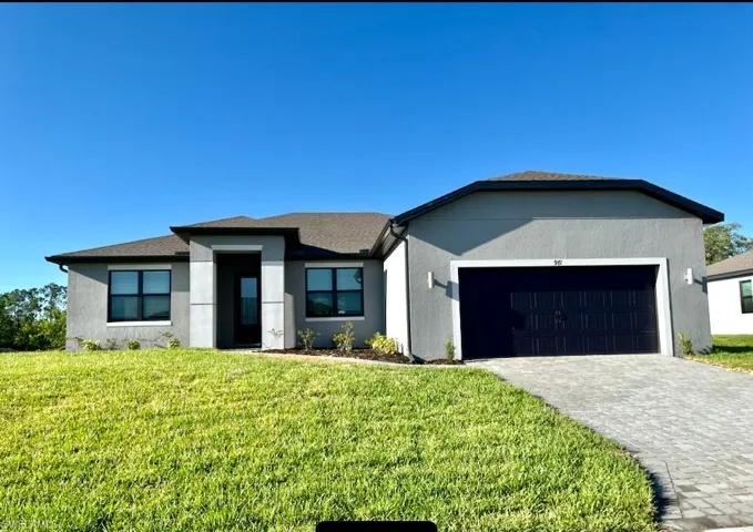 View of front of home with a garage and a front lawn