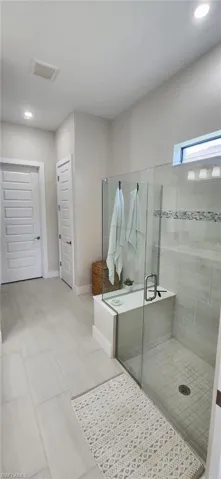 Bathroom featuring baseboards, visible vents, recessed lighting, and a stall shower