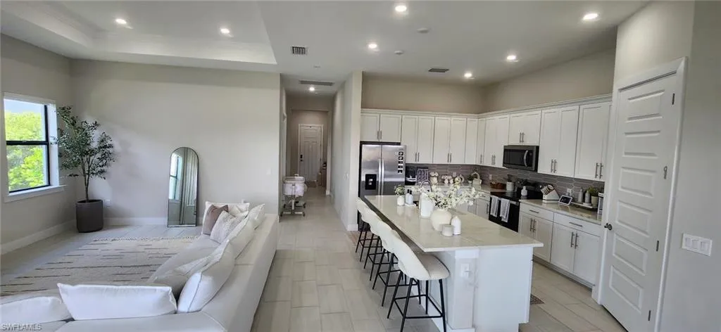 Kitchen with an island with sink, stainless steel appliances, visible vents, tasteful backsplash, and a breakfast bar area