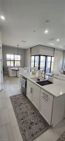 Kitchen with white cabinets, a kitchen island with sink, a sink, open floor plan, and dishwasher