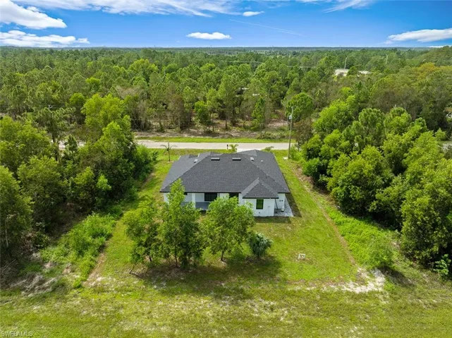 Aerial view of property and surrounding area featuring a forest