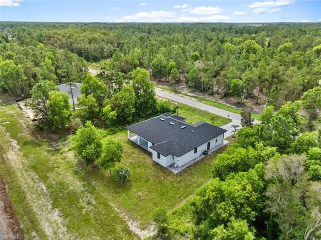 Aerial view of property and surrounding area with a forest