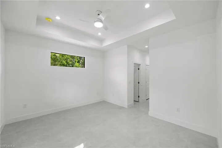 Master bedroom featuring a ceiling fan, recessed lighting, and a tray ceiling