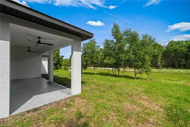 View of grassy yard with ceiling fan and a patio