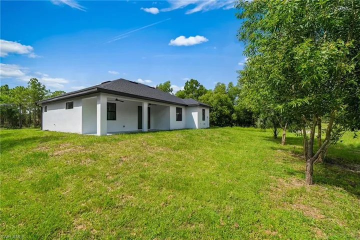Back of house with a yard, stucco siding, and a patio