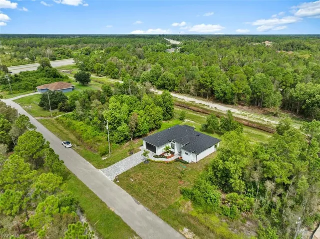 Aerial view of property and surrounding area featuring a forest