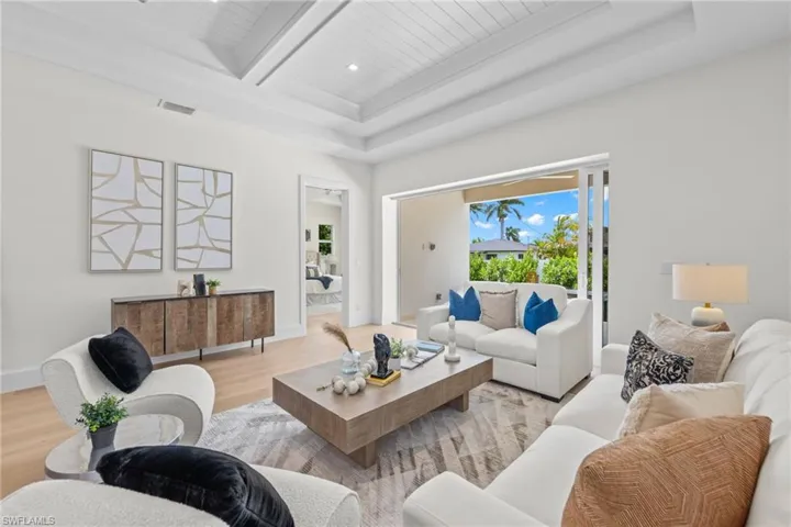 Living room featuring beamed ceiling, a tray ceiling, and wood-type flooring