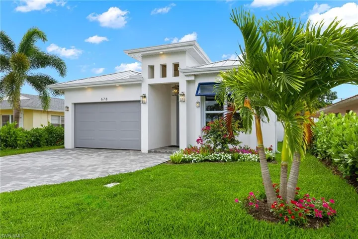 View of front of property featuring a garage and a front lawn