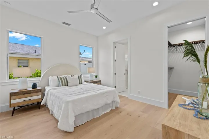 Bedroom featuring ceiling fan, multiple windows, and light hardwood / wood-style flooring