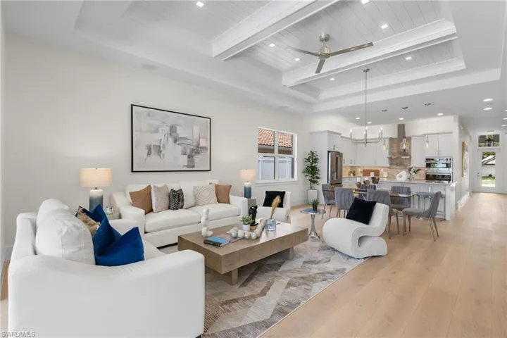 Living room with a wealth of natural light, ceiling fan, and a raised ceiling