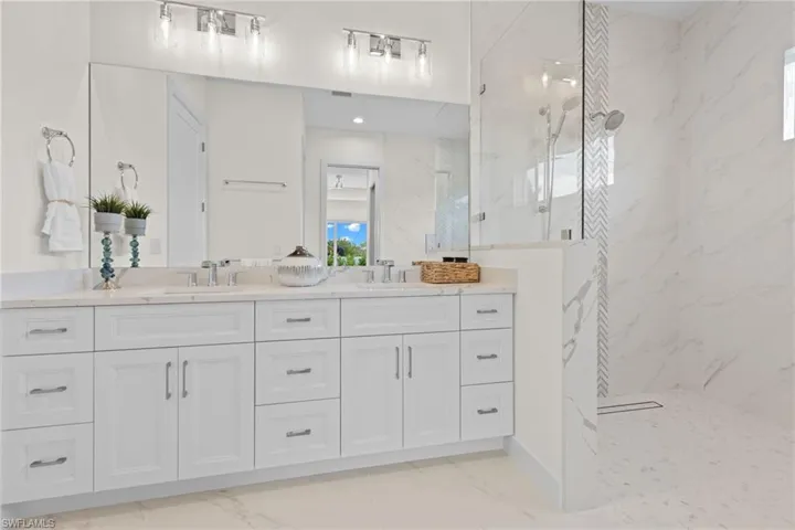 Bathroom featuring a tile shower, double sink, tile floors, and large vanity