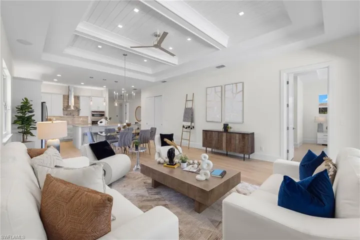 Living room featuring beamed ceiling, a tray ceiling, and light hardwood / wood-style flooring