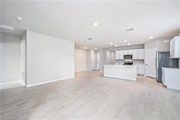 Kitchen with a kitchen island with sink, light hardwood / wood-style flooring, stainless steel appliances, sink, and white cabinetry