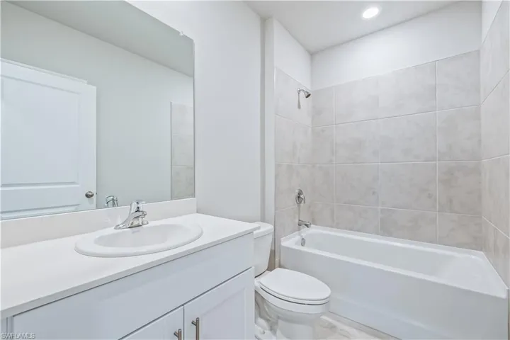 Full bathroom with toilet, tiled shower / bath, and vanity
