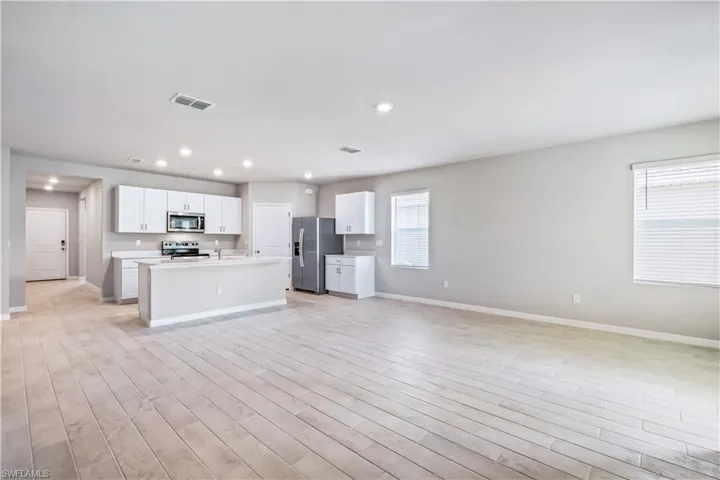 Kitchen with white cabinetry, light wood-type flooring, stainless steel appliances, and plenty of natural light