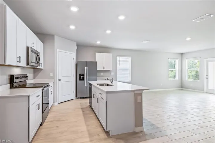 Kitchen with appliances with stainless steel finishes, sink, an island with sink, and white cabinets