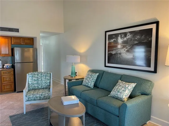 Living room featuring baseboards, a towering ceiling, visible vents, and light tile patterned floors